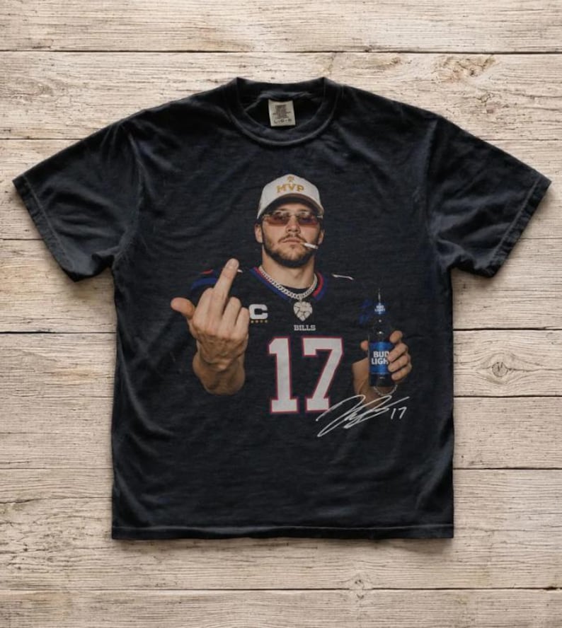 May include: A black short-sleeve t-shirt featuring a graphic print of a person wearing a white MVP cap, sunglasses, and a Buffalo Bills jersey with the number 17. The person is holding a Bud Light bottle and giving the middle finger, with a signature below.