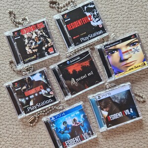 Può includere: Una collezione di sette portachiavi quadrati in miniatura, ognuno progettato come una replica di una custodia di un videogioco Resident Evil. I portachiavi presentano vari titoli di giochi, tra cui Resident Evil, Resident Evil 2, Resident Evil 3 Nemesis, Resident Evil 4, Resident Evil Code: Veronica e Resident Evil 4 per PS5 e PS4, tutti attaccati a catenelle a palline in metallo argentato.