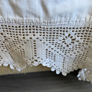 May include: White crocheted lace trim with a delicate pattern. The lace is made of cotton and has a scalloped edge.