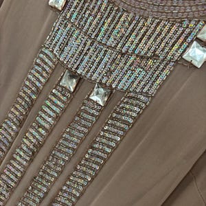 Peut inclure: Robe de soir&eacute;e taupe avec des ornements complexes de sequins et de perles. L'encolure et le haut du corsage pr&eacute;sentent des rang&eacute;es de petits sequins iris&eacute;s et de plus gros cristaux carr&eacute;s et transparents. La robe est &eacute;tiquet&eacute;e "ANNA PAPELL EVENING" et taille 18W.