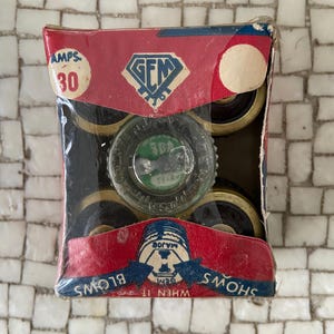 May include: A vintage package of GEM brand electrical fuses. The red and blue box features the GEM logo and the text "AMPS 30". The package contains several fuses with black and gold components. The text "WHEN IT SHOWS BLOWS" is also visible.