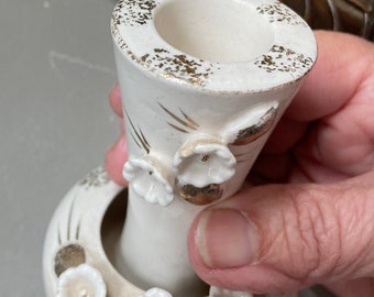 May include: White ceramic vase with gold accents and floral designs. The vase has a wide base and a narrow neck.