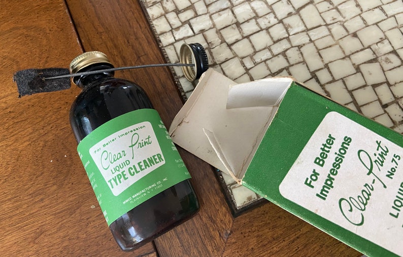 May include: A green box with the text "For Better Impressions Clear-Print Liquid No. 75" and a brown glass bottle with a green label that reads "Clear Print Liquid Type Cleaner" and a black applicator.