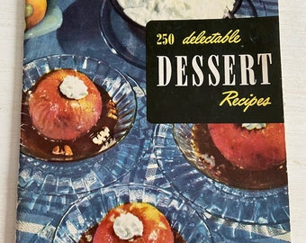 May include: A vintage cookbook cover with the title "250 delectable DESSERT Recipes". The cover features a blue and white patterned tablecloth with three glass dishes containing red apples topped with whipped cream and a brown sauce.