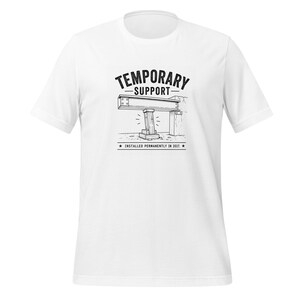 Może przedstawiać: Biały t-shirt z krótkim rękawem z czarną grafiką przedstawiającą drewniany słup podpierający stalową belkę. Tekst TEMPORARY SUPPORT znajduje się powyżej, a INSTALLED PERMANENTLY IN 2017 poniżej, w otoczeniu dwóch małych czarnych gwiazdek.
