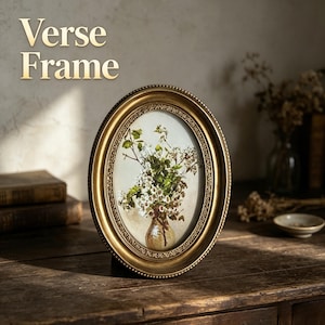 May include: An oval gold-toned picture frame with a beaded edge and an inner decorative border. The frame contains an illustration of white flowers in a glass vase. The text "Verse Frame" is printed in the upper left corner of the image.