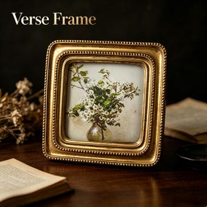 May include: A square gold picture frame with a beaded inner border and a distressed finish. The frame contains an image of white flowers in a glass vase. The text "Verse Frame" is printed in gold in the upper left corner of the image.
