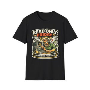 May include: A black short-sleeve t-shirt featuring a graphic illustration of a person wearing a headset at a computer. The text reads READ-ONLY FRIDAY and NO CHANGES PERMITTED! The design includes a computer monitor with a warning icon and a coffee mug.