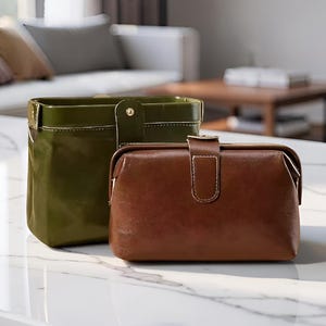 Peut inclure: Deux pochettes rectangulaires dotées d'une ouverture à cadre articulé et d'une fermeture à bouton-pression unique. L'une est vert olive foncé, l'autre est marron. Les deux présentent des coutures blanches visibles et une forme structurée.