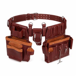 May include: A dark brown leather tool belt featuring multiple pouches, pockets, and loops for organization. The belt includes a metal buckle, silver-toned rivets, a metal hammer holder, and a small hanging chain, all constructed with reinforced stitching.