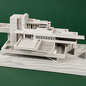 May include: A monochromatic light gray architectural scale model of a multi-level building with cantilevered sections, flat roofs, and rectangular windows. The structure is mounted on a base featuring molded, wavy, horizontal lines representing water.