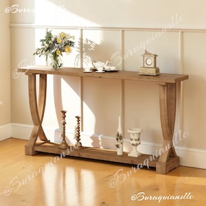 May include: A long, rectangular wooden console table featuring a natural light brown finish and curved, X-shaped side supports. The table includes a lower shelf and a flat top surface, providing a stable structure for displaying various decorative items.
