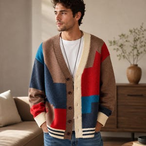 May include: A long-sleeve button-up cardigan featuring a colour-blocked design in shades of brown, navy blue, red, and cream. The knit garment has a V-neckline, ribbed cuffs, and a ribbed hem with horizontal stripes, worn over a plain white t-shirt.