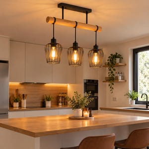 Puede incluir: Una lámpara colgante de tres luces con una viga de madera clara horizontal suspendida por varillas de metal negro. Tres pantallas de jaula de alambre negro cuelgan de la viga, cada una con una bombilla estilo Edison de luz cálida.