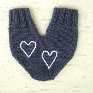 May include: Dark blue knitted mittens with white heart embroidery. The mittens are made of a soft, textured yarn and feature a ribbed cuff. The design includes two white hearts, one on each mitten.