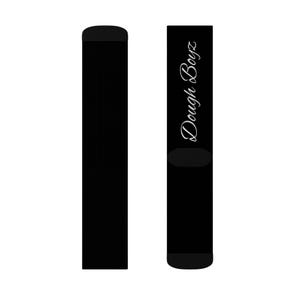 Puede incluir: Un par de calcetines negros. El calcetín izquierdo es negro liso. El derecho presenta el texto Dough Boyz escrito verticalmente en una fuente cursiva blanca a lo largo del lateral. Los calcetines tienen la zona del talón y la puntera en negro.