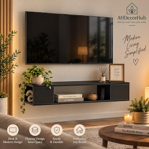 May include: A black wall-mounted floating shelf featuring an open central compartment and two enclosed side cabinets. The shelf holds books, a small decorative object, and a remote control, positioned beneath a large flat-screen television.