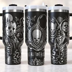 Op de afbeelding: Een zwarte roestvrijstalen beker met handvat en witte deksel, voorzien van een gedetailleerde monochrome grafische print van horrorfilmpersonages zoals Jason Voorhees, Pennywise en Michael Myers, met de tekst "WE ALL FLOAT HERE" en "SAY HIS NAME".