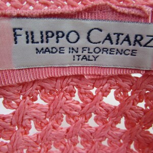 May include: A pink woven hat with a white label that reads "Filippo Catarzi Made in Florence Italy".