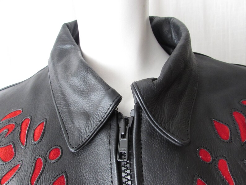 May include: Black leather jacket with a red floral design. The jacket has a zipper closure and a collar.