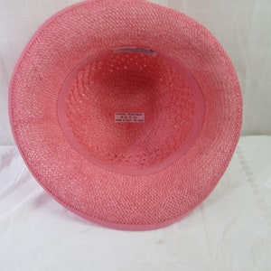 May include: Pink straw hat with a woven texture. The hat has a label inside that reads "100% Paper, Size 57, Made in Italy".