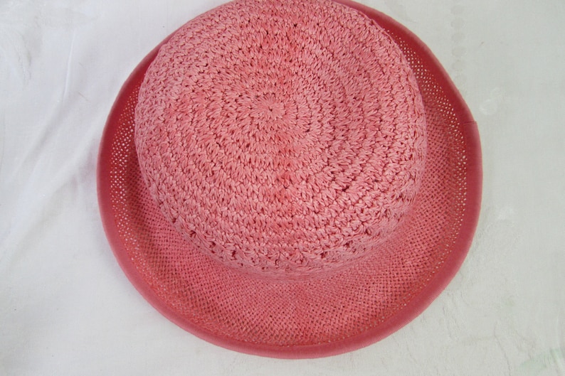 May include: A pink crocheted sun hat with a wide brim.