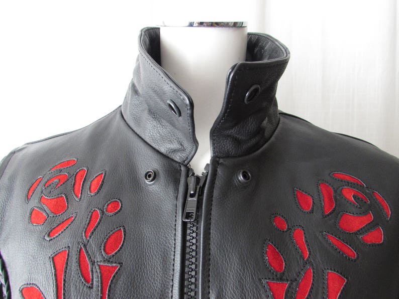 May include: Black leather jacket with a zipper closure and red embroidered roses on the front.