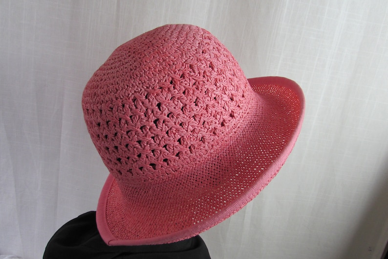 May include: A pink crocheted sun hat with a wide brim.