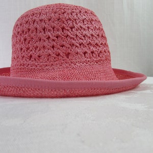 May include: A pink crocheted sun hat with a wide brim.
