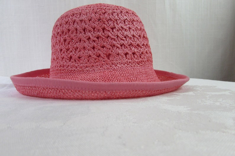 May include: A pink crocheted sun hat with a wide brim.