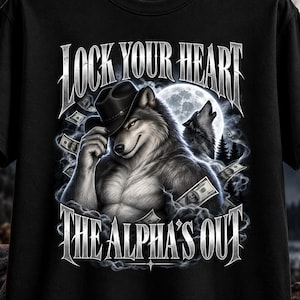 Può includere: Una t-shirt nera con la grafica di un lupo muscoloso che indossa un cappello da cowboy, circondato da banconote fluttuanti e fumo. Il testo recita LOCK YOUR HEART in alto e THE ALPHA'S OUT in basso con un carattere argentato.