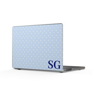 May include: A light blue laptop skin featuring a repeating pattern of small white polka dots. The bottom right corner displays the dark blue capital letters SG in a serif font. The skin is applied to the exterior lid of a closed laptop.