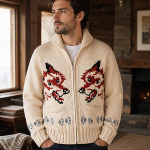 Puede incluir: Una chaqueta de punto color crema con cremallera, cuello de chal y dos bolsillos delanteros. El suéter muestra dos motivos simétricos de cabezas de zorro en rojo, negro y blanco en el pecho y una fila de pequeños patrones florales azules en el dobladillo.
