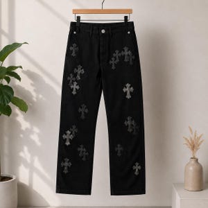 May include: Black denim pants featuring a straight-leg cut and a high-waisted design. The fabric is adorned with multiple dark grey cross-shaped patches scattered across the front panels. The trousers include a button closure and belt loops.