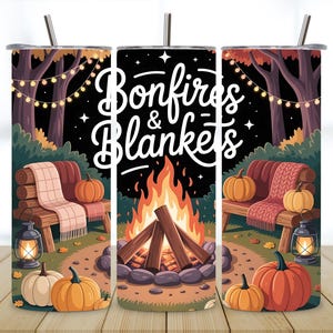 May include: A cylindrical tumbler with a straw featuring a fall-themed graphic of a bonfire, pumpkins, a wooden bench with a blanket, and string lights. The text "Bonfires & Blankets" is printed in white script against a dark night sky background.