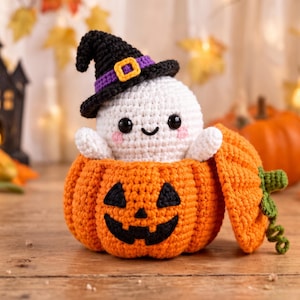 Peut inclure: Un fantôme blanc crocheté avec des yeux noirs et des joues roses portant un chapeau de sorcière noir avec une bande violette et une boucle jaune, assis dans une citrouille orange crochetée avec un visage noir et un couvercle.