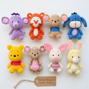 May include: A set of eight crocheted amigurumi figures featuring various animal characters in vibrant colors, including a purple elephant, orange tiger, tan mouse, blue donkey, yellow bear, tan kangaroo, pink piglet, and yellow rabbit with a tag reading Handmade Amigurumi Bundle - Set of 8.