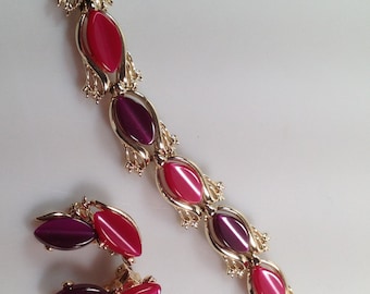 May include: A gold tone bracelet and earrings set with alternating pink and purple oval shaped stones.