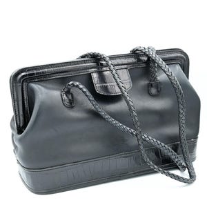 Puede incluir: Un bolso de m&eacute;dico de cuero negro con una correa trenzada y un patr&oacute;n de cocodrilo en relieve.