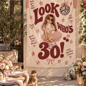 May include: A cream-coloured fabric banner featuring the dark red text Look Who's 30!, a central photograph of a child in a pink tutu and heart-shaped sunglasses, and decorative illustrations of a disco ball, cherries, stars, and bows.