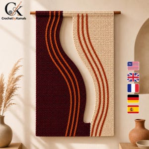 Op de afbeelding: Een rechthoekige wandhanger met een tweekleurig haakontwerp in donkerbordeaux en crème. Het stuk is verdeeld door een gebogen lijn, geaccentueerd met drie verticale oranje garenstrepen aan elke kant, en opgehangen aan een houten roede.