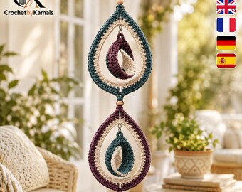 Puede incluir: Una decoración colgante vertical con dos marcos de ganchillo en forma de lágrima en azul cerceta oscuro y morado intenso. Cada marco contiene un elemento de ganchillo más pequeño en forma de media luna, acentuado con cuentas de madera.