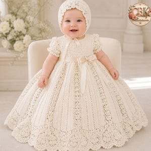 Könnte beinhalten: Ein cremeweißes Häkelkleid mit kurzen Puffärmeln, einem weiten Rock mit komplizierten spitzenartigen Mustern und einem Satinband in der Taille. Das Outfit enthält eine passende Häkelhaube, die das Gesicht mit einem gewellten Rand umrahmt.