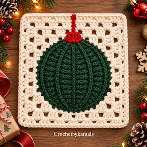 Op de afbeelding: Een vierkant gehaakt granny square met een donkergroen cirkelvormig ornamentontwerp in het midden, voorzien van een rode dop en hanger. De rand is gemaakt van crèmekleurig garen in een klassiek opengewerkt patroon. De tekst Crochetbykamals staat eronder.