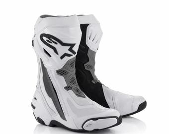 Könnte beinhalten: Ein Paar weiß-schwarz-graue Motorradstiefel mit hohem Schaft, verstärkten Schutzpaneelen, Belüftungseinsätzen aus Mesh und dem Alpinestars-Logo, das deutlich an der Außenseite des oberen Schaftbereichs angebracht ist.