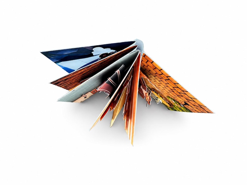 May include: A fan-folded book with multiple pages spread open, displaying various printed images including a blue sky, a brick wall, and abstract patterns in shades of orange, brown, and black, creating a star-like geometric shape.