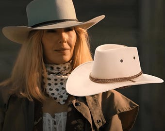 May include: A white cowboy hat featuring a braided brown rope hatband and two metal ventilation eyelets on each side of the crown. The hat has a structured brim and a smooth finish, presented as a distinct accessory item.