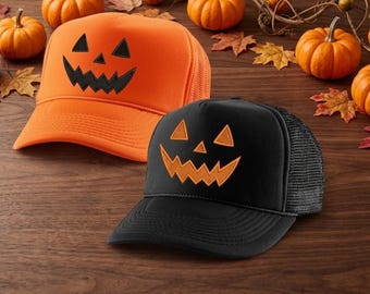 May include: Two trucker caps with mesh backs. One cap is bright orange with a black embroidered jack-o'-lantern face. The other cap is black with an orange embroidered jack-o'-lantern face. Both caps feature a structured front panel and a brim.