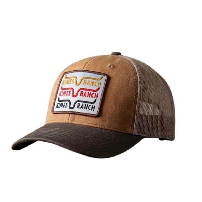 May include: A tan and dark brown baseball cap with a mesh back. The front features a rectangular patch with the text KIMES RANCH in yellow, red, and black, accompanied by a stylized horn logo above each line of text on the white background.