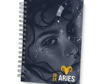 May include: A spiral-bound notebook featuring a dark, monochromatic illustration of a face with flowing hair. The cover displays a circular zodiac chart, a yellow ram icon, and the text 20 24 ARIES printed in white and yellow lettering.